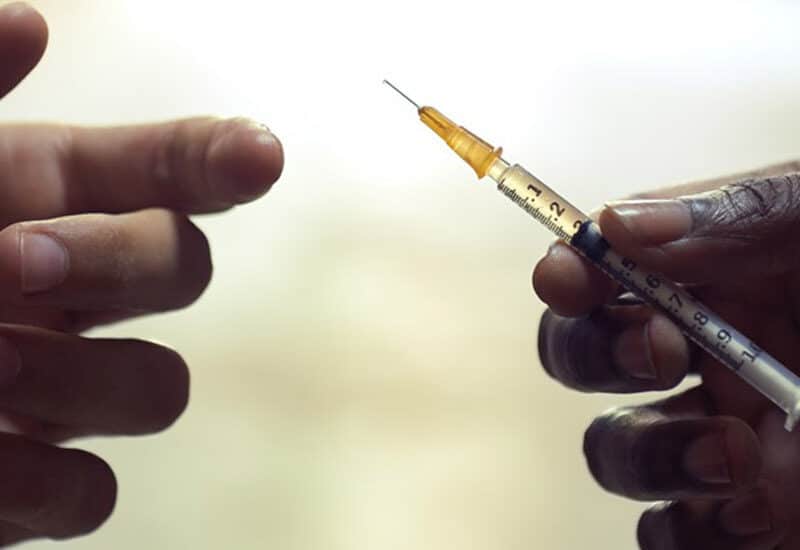 cropped images of hands sharing a needle filled with intravenous drugs