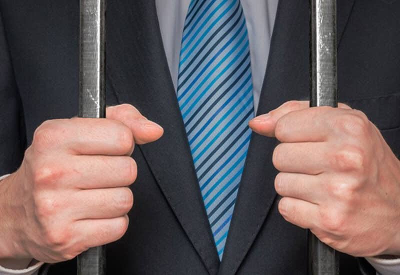 cropped image of man in suit behind bars in jail for traffic offences