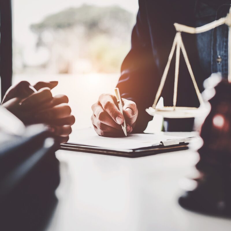business-woman-and-lawyers-discussing-contract-papers-with-brass-scale-on-wooden-desk-in-office-law-legal-services-advice-justice-concept