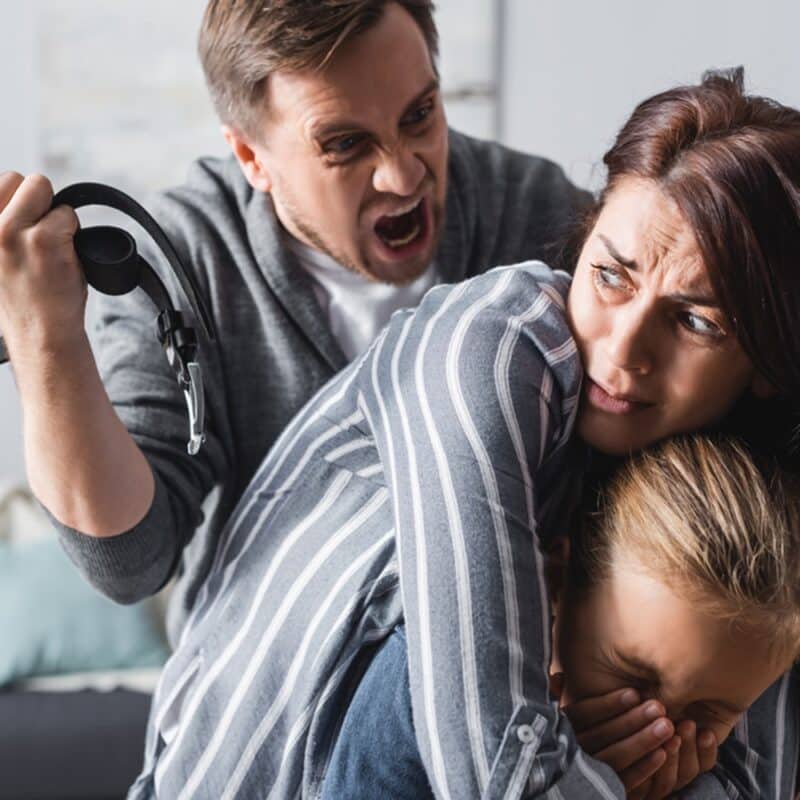 woman protecting child from angry man with belt in had an angry facial expression