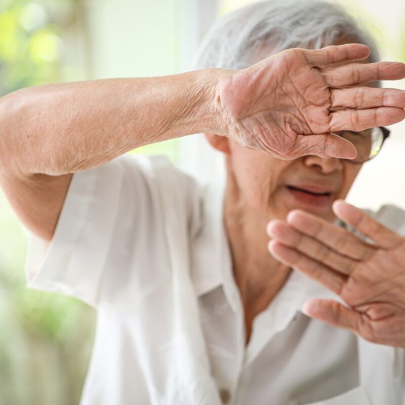 woman shielding face with hands
