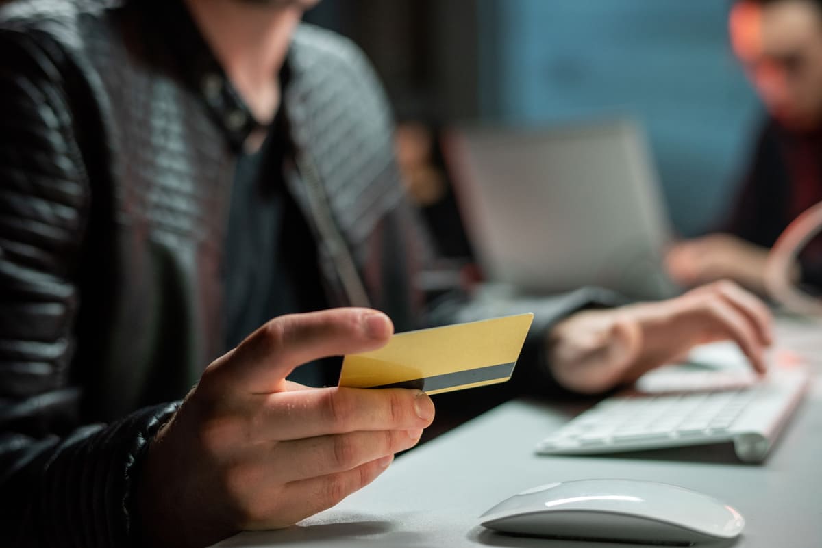 Person holding a bank card at a keyboard depicting fraud