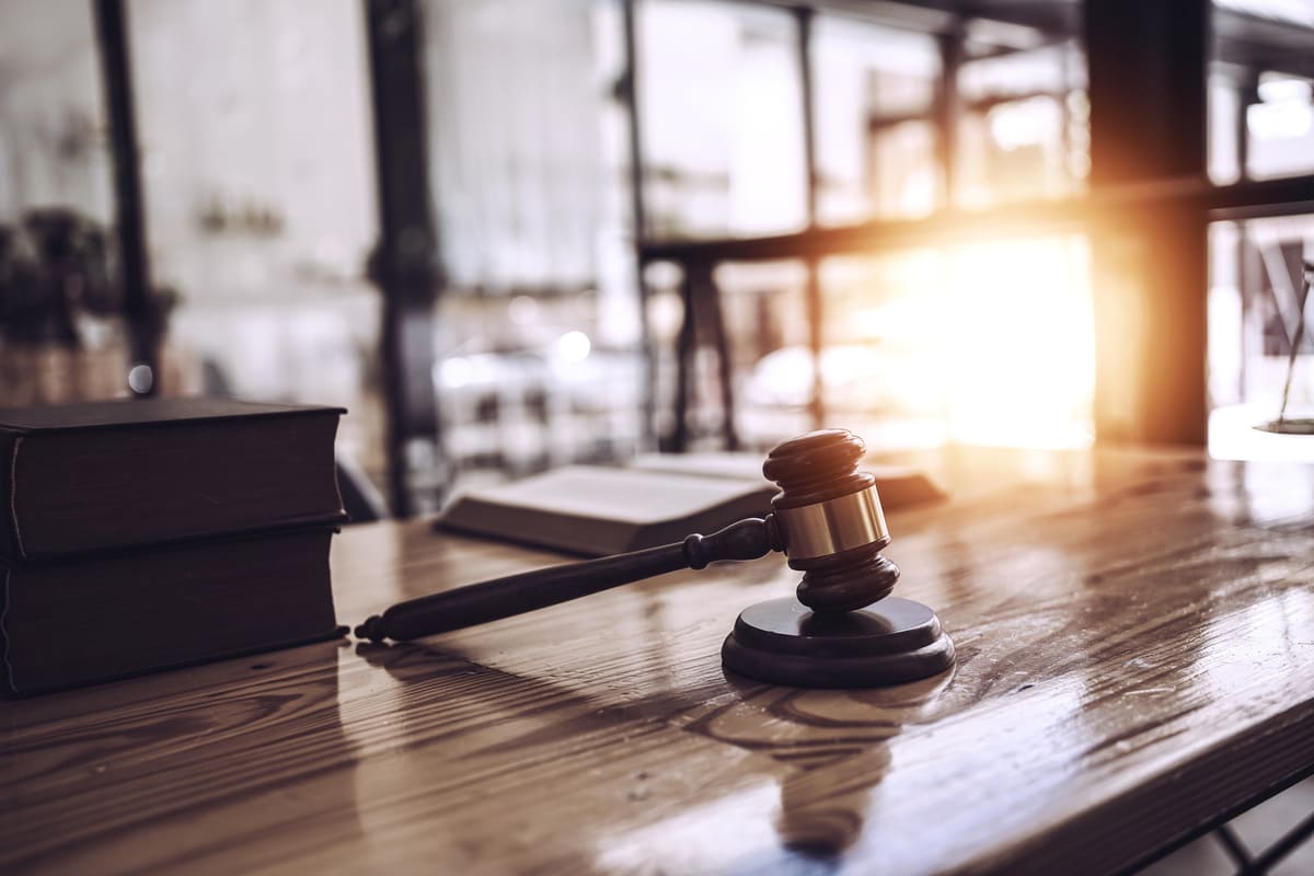 Gavel on a wooden desk in warm light beside law books
